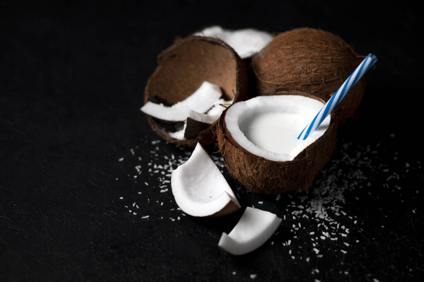 natural fresh coconut milkshake on a dark black background, milk in a plate of coconut - Фото, изображение