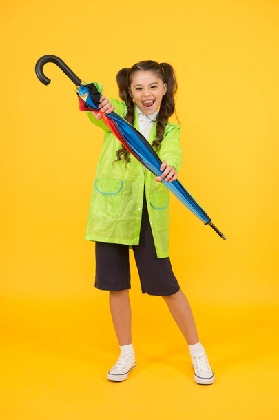 feel protected and happy. accessory for fall season. autumn kid fashion. dry and comfortable in rainy weather. small girl in raincoat with umbrella. schoolgirl waterproof raincoat. in good mood - Zdjęcie, obraz
