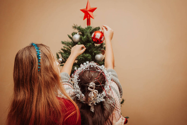 Two girls decorating the Christmas tree - Foto, imagen