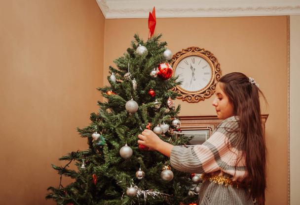 Girl decorating the Christmas tree - Foto, afbeelding