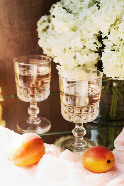 Rose wine in glasses. Rose wine on golden bottles background with flowers and fruits - Fotografie, Obrázek