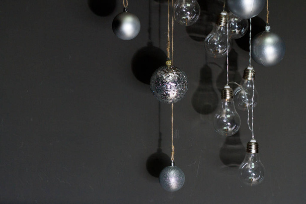 Fondo de Año Nuevo o Navidad, primer plano de burbujas de Navidad plateadas y guirnalda de bombillas en un fondo oscuro, enfoque selectivo
 - Foto, imagen