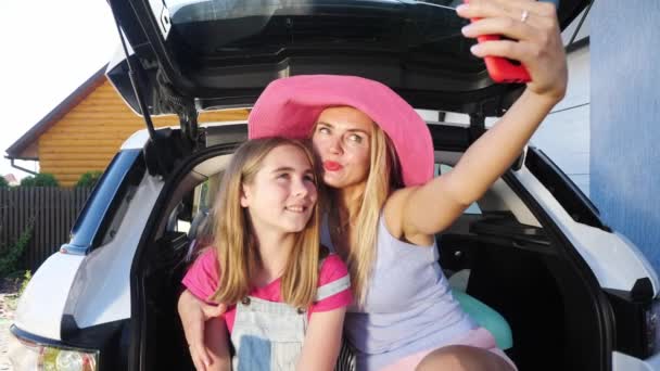 Une fille avec sa mère est assise à l'arrière de la voiture et fait un selfie
. - Séquence, vidéo