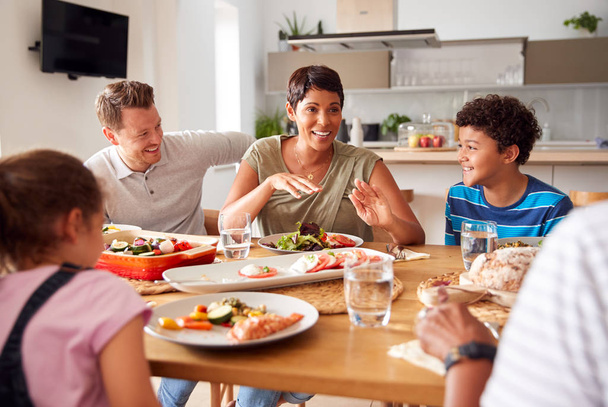 Multi-Generation Mixed Race Family Eating Meal Around Table At Home Together - Photo, image