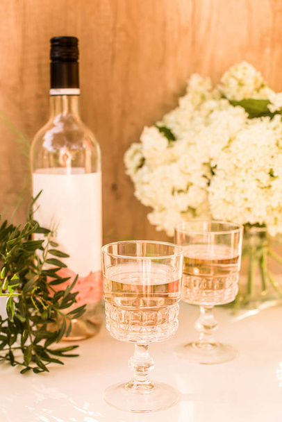Ruusuviiniä laseissa. Ruusuviini kultaisilla pulloilla taustalla kukkia ja hedelmiä
 - Valokuva, kuva