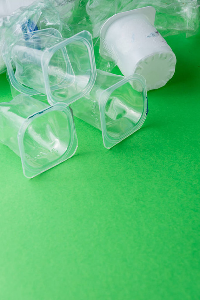 Vista superior de recipientes de plástico em fundo verde, prontos para reciclagem, verticalmente com espaço de cópia
 - Foto, Imagem