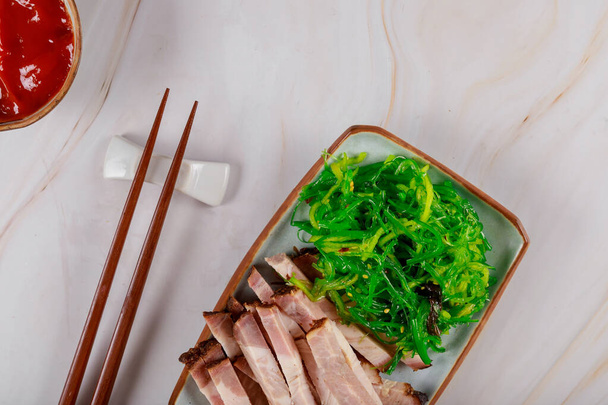 Seaweed strips of grilled meat with sauce and chopstick - 写真・画像