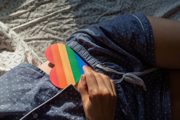 Woman holds in hands a heart in the colors of the rainbow. Young beautiful girl. LGBT history month. Pride Month. Lesbian Gay Bisexual Transgender. LGBT flag. Love, human rights, tolerance. LGBTQ+ - 写真・画像