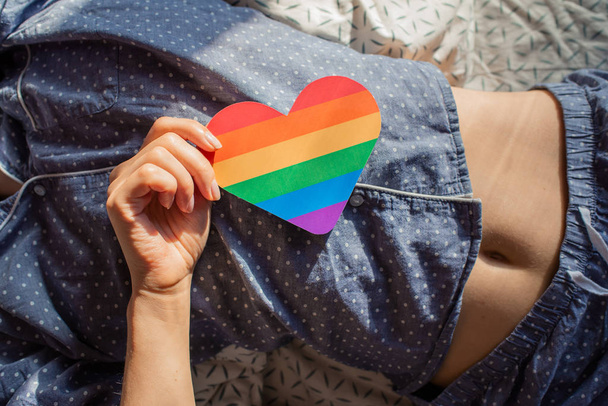 Woman holds in hands a heart in the colors of the rainbow. Young beautiful girl. LGBT history month. Pride Month. Lesbian Gay Bisexual Transgender. LGBT flag. Love, human rights, tolerance. LGBTQ+ - Фото, зображення