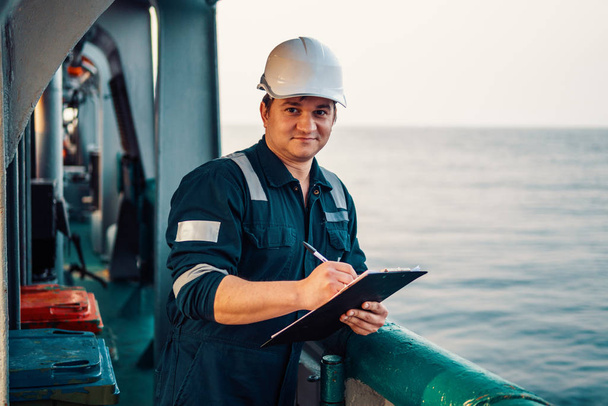 Güverte görevlisi offshore gemi veya gemi güvertede, PPE kişisel koruyucu ekipman giyiyor. Kontrol listesini doldurur. Denizdeki evraklar - Fotoğraf, Görsel