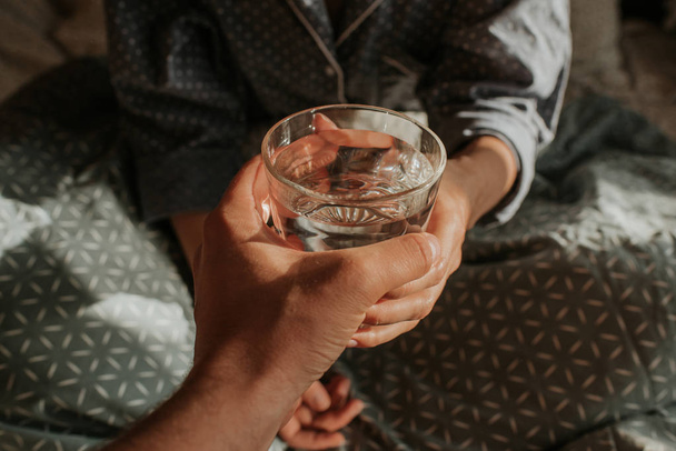 Woman in bed holding a glass of water in hand. Happy morning. Girl in pajamas. Healthy lifestyle, wellness. Proper nutrition. Drinking water. Morning with water. Sunlight on linens. Pillow, blanket - Fotoğraf, Görsel