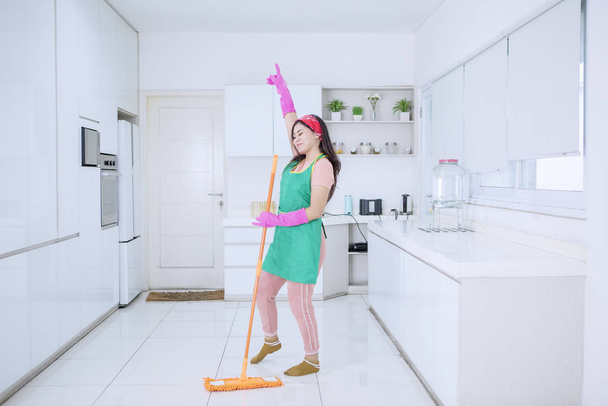 Beautiful woman dancing joyfully while mopping - Foto, Bild