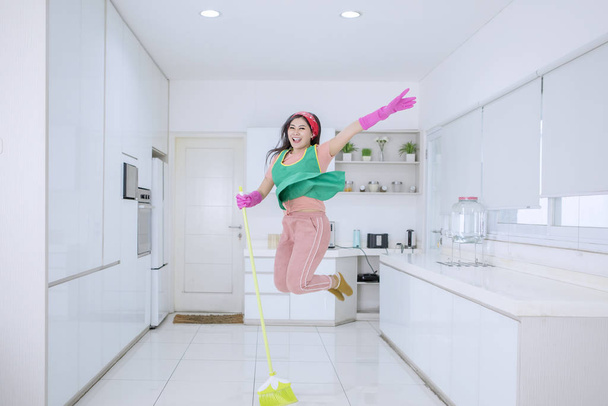 Beautiful woman jumping happily while sweeping - Photo, Image