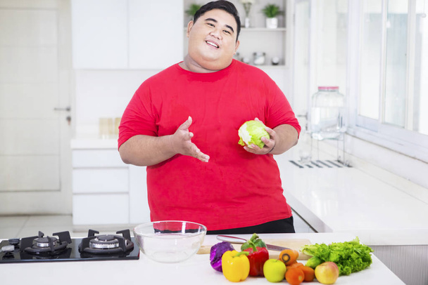 Fat Asian man holding an apple happily - Фото, изображение