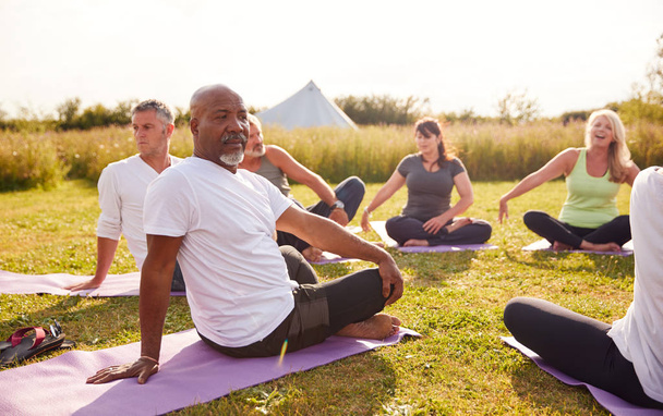 Female Teacher Leading Group Of Mature Men And Women In Class At Outdoor Yoga Retreat - Photo, Image