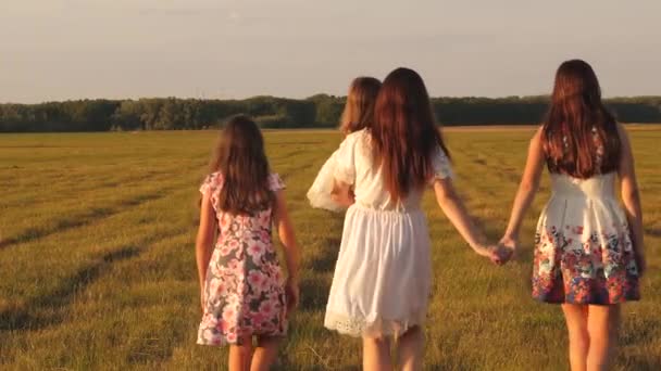 mother and little daughter with sisters walking in park holding hands. Children and mom are playing in meadow. concept of a happy family. Happy young family with a child walking on a summer field. - Footage, Video