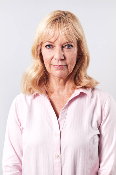 Studio Shot Of Mature Woman With Serious Expression Against White Background At Camera - Foto, Bild