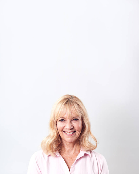 Studio Shot Of Smiling Mature Woman Against White Background At Camera - Photo, Image