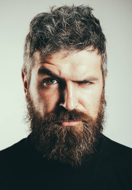Serious stylish bearded man. Handsome young man isolated. Close up portrait of severe hot bearded guy with stylish hairdo. Isolated on grey background. Lifestyle people concept. Bearded man. - 写真・画像