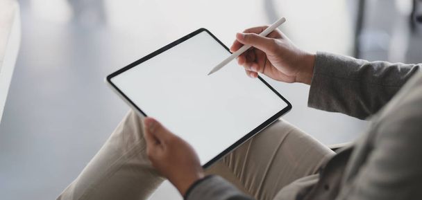 Крупним планом молодий бізнесмен використовує порожній планшет під час роботи над своїм проектом
  - Фото, зображення