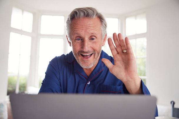 Volwassen man hebben van online overleg met arts thuis op laptop - Foto, afbeelding