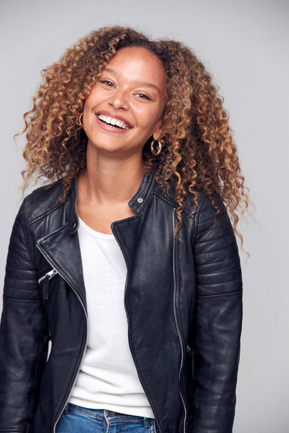 Waist Up Studio Shot Of Happy Young Woman Wearing Leather Jacket Smiling At Camera - Foto, immagini