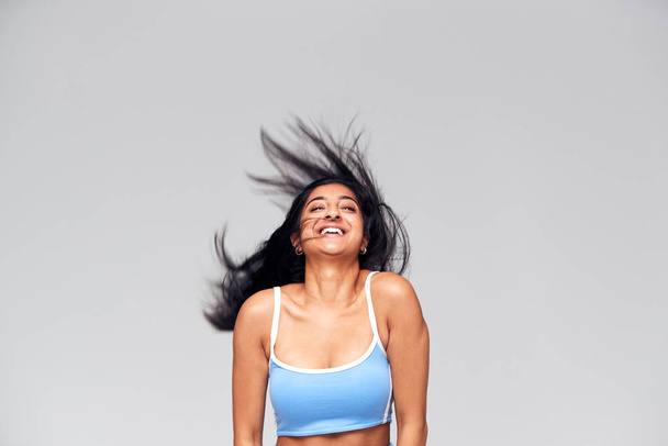 Studio Portrait Of Positive Happy Young Woman Flicking Long Hair - Фото, изображение