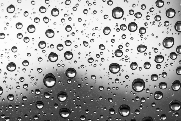 Vesipisarat lasi-ikkunan harmaalla pohjalla syksyn sateen jälkeen
. - Valokuva, kuva