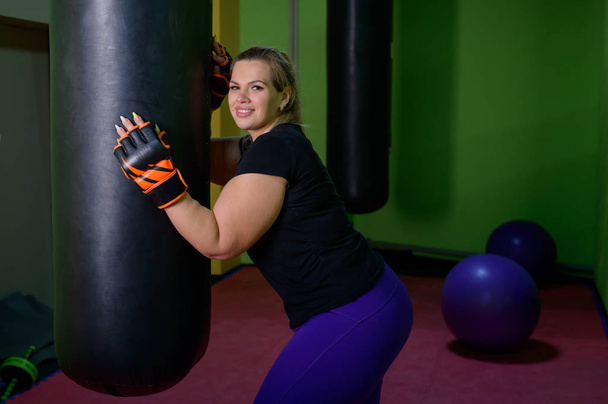 Fat woman beats a punching bag in the gym. Way to lose weight. - Fotografie, Obrázek
