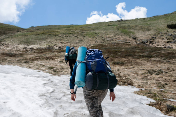 バックパックを持つ観光客は、丘、雪を行く - 写真・画像