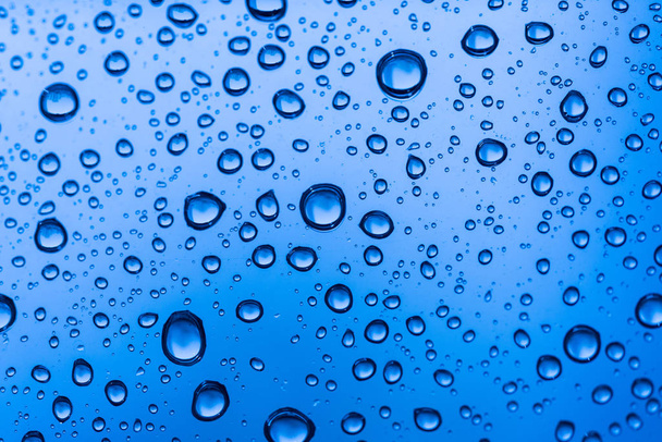 Water drops on glass window blue background after the rain in the autumn fall. - Photo, image