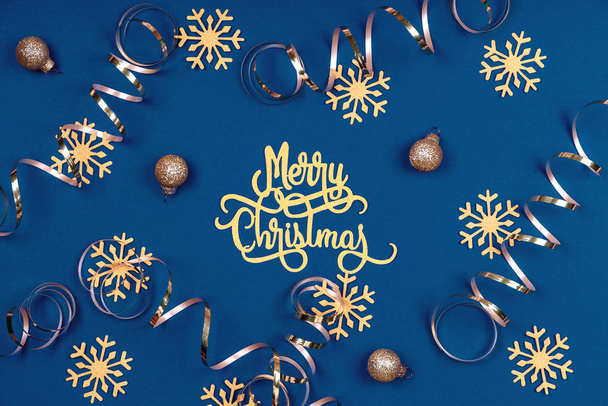 Fundo de férias com palavras de Feliz Natal, flocos de neve dourados, bolas e fitas em azul clássico
 - Foto, Imagem