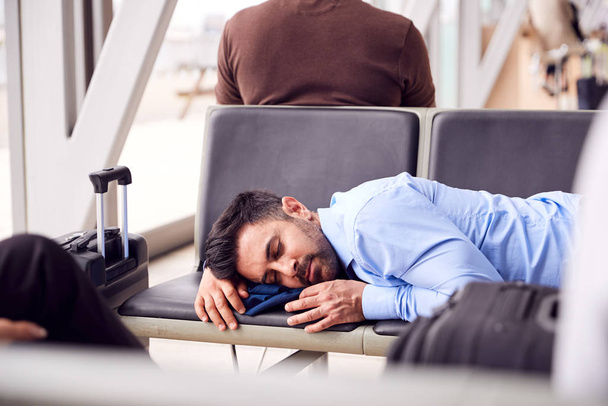 Businessman Sleeping On Seats In Airport Departure Lounge Because Of Delay - Фото, изображение