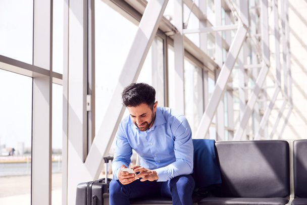 Businessman Sitting In Airport Departure Lounge Using Mobile Phone - Фото, зображення