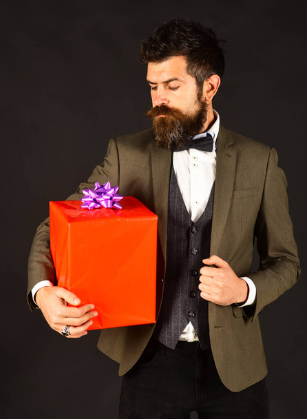 Man with beard holds present. Businessman with serious face - Fotó, kép