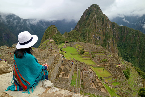 Γυναίκα ταξιδιώτης κάθεται στο βράχο κοιτάζοντας τα ερείπια Inca του Machu Picchuin Cusco Περιφέρεια, επαρχία Urubamba, Περού - Φωτογραφία, εικόνα