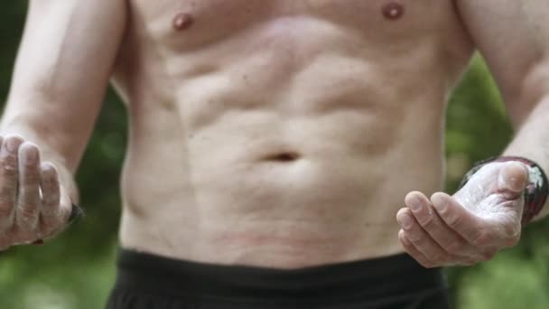 mittlere Aufnahme eines muskulösen Brustkorbs und eines Paares Hände mit Talkumpuder - Filmmaterial, Video