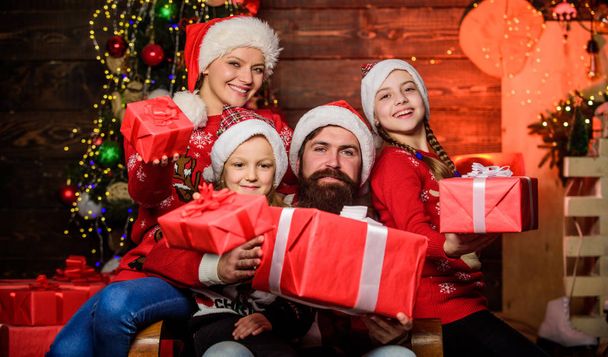 Rodiče a děti otevírají vánoční dárky. Otec Santa Claus a matka dcerušky vánoční stromeček pozadí. Vánoční tradice. Rodinná pouta. Vánoční radost. Šťastné svátky - Fotografie, Obrázek