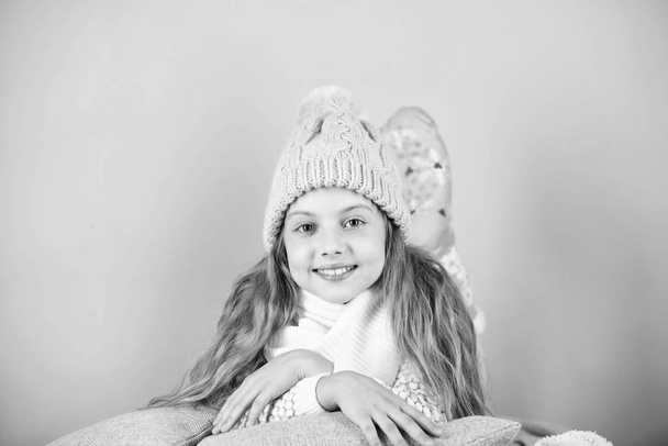 Warm accessories that will keep you cozy this winter. Kid girl wear knitted hat relaxing pink background. Child long hair warm woolen hat enjoy warm. Warm clothes concept. Keep warm and comfortable - Foto, imagen