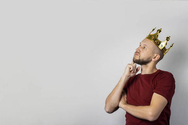 Young man with a crown on his head on a light background. Concept is king, luck, gain, rich, dream, goal, aspiration. Banner - 写真・画像