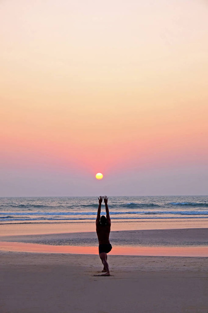 Um homem irreconhecível fazendo uma saudação do sol da posição do ioga em um
 - Foto, Imagem