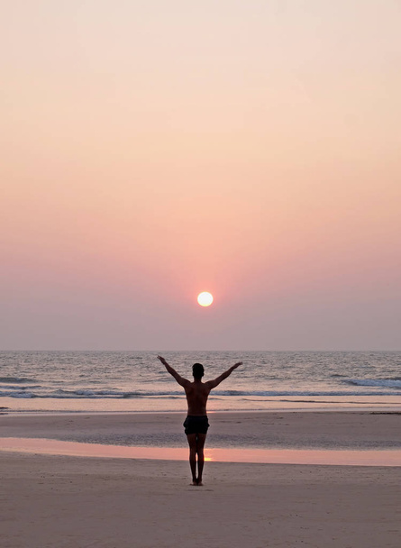 Nierozpoznawalny mężczyzna uprawiający jogę salutując na słońcu - Zdjęcie, obraz