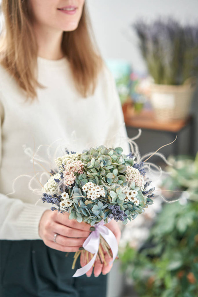 Colourful beautiful bouquet of mixed dried flowers in woman hand. the work of the florist at a flower shop. - Foto, imagen