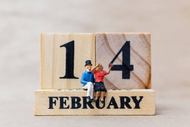 Miniature people couple with wooden block 14 FEB on wooden background - 写真・画像