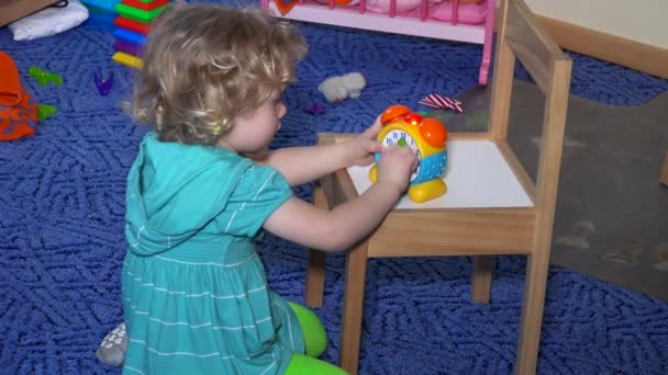 Kleines Kind spielt mit Spielzeuguhr. Lernzeit für Spielzeug-Handuhr - Filmmaterial, Video
