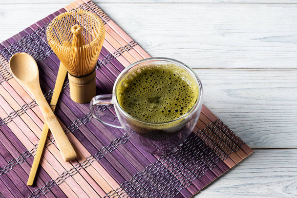 Green matcha tea drink and accessories on a white wooden background. Japanese tea ceremony concept. - Photo, image