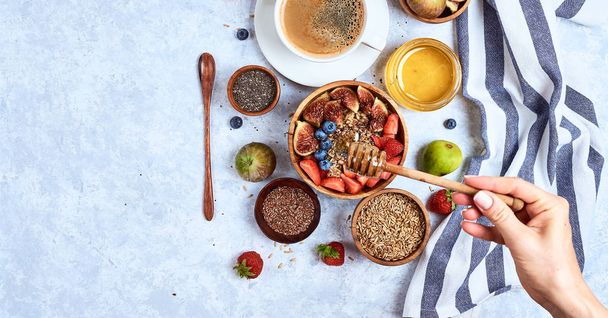 Top view showing hands eating porridge with honey, blueberries, strawberries on blue wooden table background Good morning, healthy breakfast background - Foto, imagen