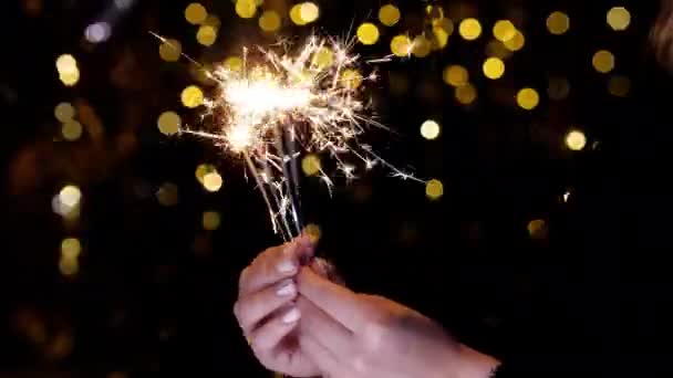 The burning sparkler flashes brightly in hands and the golden sparks fly apart. - Footage, Video