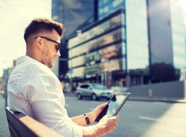 Man met tablet pc zittend op stad straat bankje - Foto, afbeelding
