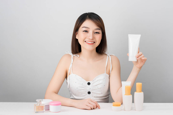 concetto di salute e bellezza - Attraente donna asiatica che applica la crema sulla pelle, isolata su sfondo bianco
. - Foto, immagini